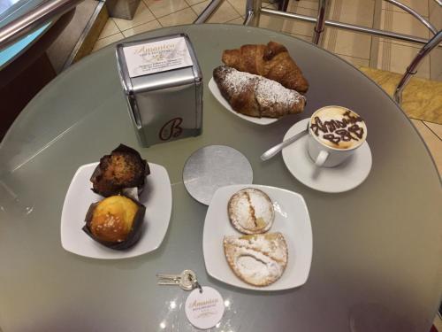 a table with three plates of pastries and a cup of coffee at Amantea Monument in Terrasini