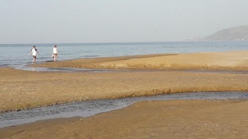 two people walking on the beach near the water at 360 Panorama House - Gazing at Horizon and the Stars of the Galaxy in the night - Fresh Cool breeze most of the time - just 7 min from the beach in Kournás