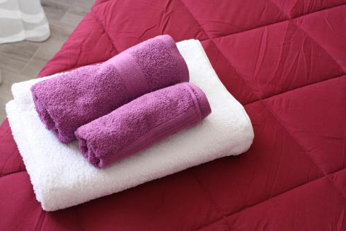 a purple and white towel sitting on a bed at House of colours - Relax, arte e confort per coppie, famiglie e gruppi in Alghero
