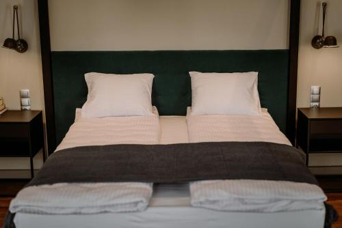 a large bed with a green headboard and white pillows at BIKE ROOMS in Przemyśl
