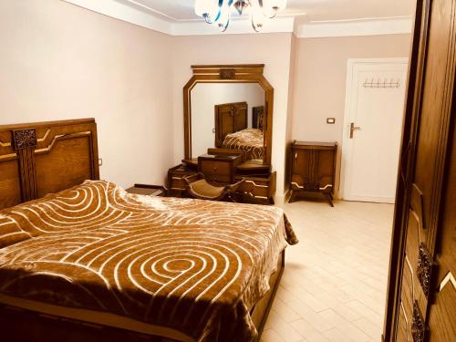 1 dormitorio con cama y espejo grande en Toscanini Apartament اول صف مباشره, en Alejandría