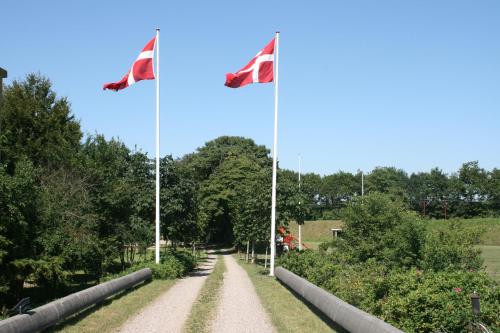two flags flying over a dirt road at Toscana Restaurant and Bed & Breakfast in Padborg