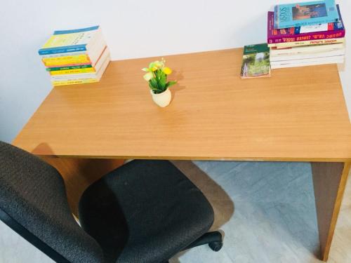a wooden desk with books and a vase of flowers on it at Khan Alsira - חאן אלסרה in Alsira