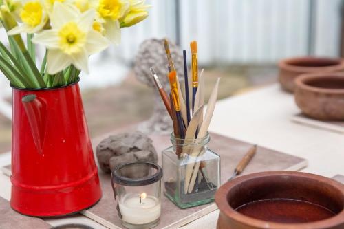a red vase with flowers and a candle on a table at JustB Edinburgh in Edinburgh