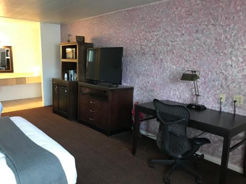 a hotel room with a desk with a television and a bed at Country West Motel of Rock Springs in Rock Springs