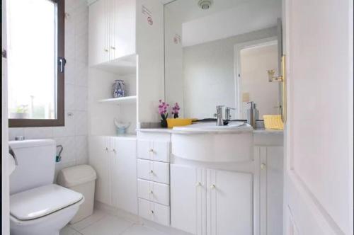 a white bathroom with a sink and a toilet at ADOSADO DE LUJO CON PISCINA PRIVADA en ZONA MUY TRANQUILA in Gandía