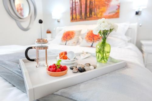 a tray with fruit and a vase of flowers on a bed at JustB Edinburgh in Edinburgh