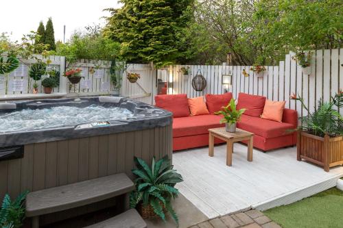 a hot tub in a backyard with a red couch at JustB Edinburgh in Edinburgh