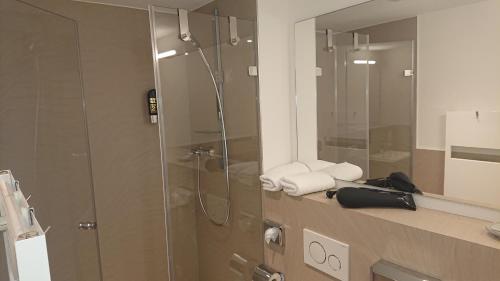 a bathroom with a shower and a sink with towels at Apart-House Nürnberg in Nürnberg