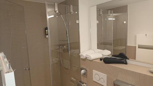a bathroom with a shower and a sink with towels at Apart-House Nürnberg in Nuremberg
