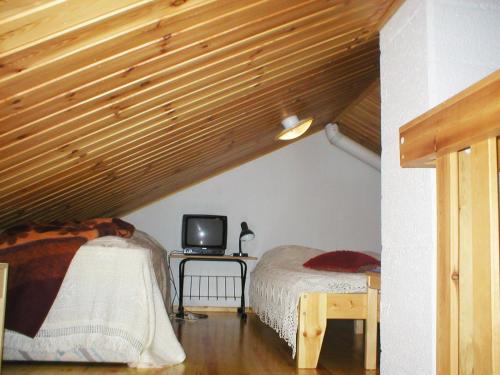 a bedroom with two beds and a table with a tv at Ylläsriemu Apartments in Äkäslompolo