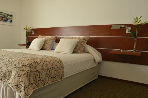 a bedroom with a large bed with a wooden headboard at Hotel de la Cañada in Cordoba