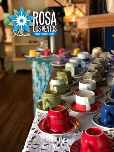 a long line of plates and cups on a table at Pousada Rosa dos Ventos in Praia do Forte
