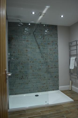 a bathroom with a shower with a brick wall at The Manor House at Quorn in Loughborough