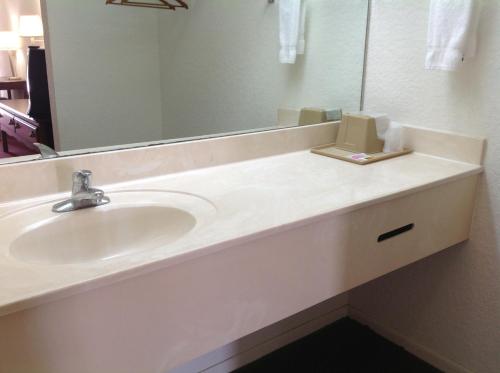 a bathroom with a sink and a mirror at Budget Host Hempstead Inn Brookhollow/Energy Corridor in Houston