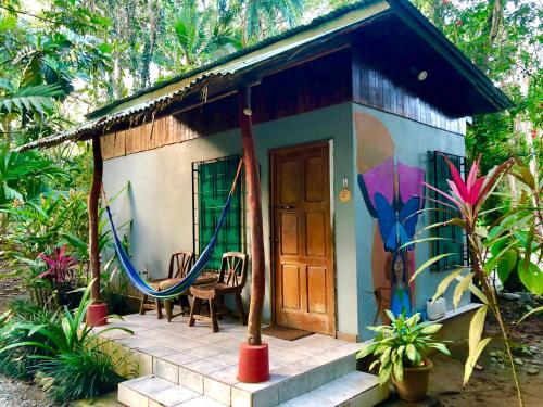 ein kleines Haus mit einer Tür und einer Veranda in der Unterkunft Tasty Dayz Hostel in Puerto Viejo