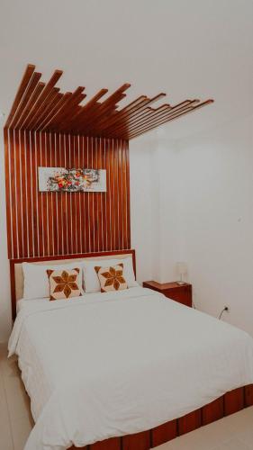 a bedroom with a white bed with a wooden headboard at Seaview Beach Resort in Jepara