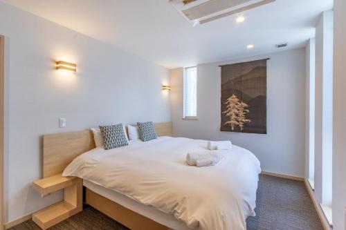 1 dormitorio con 1 cama grande con sábanas blancas en Owl House Niseko, en Niseko