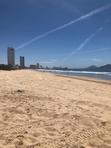 a beach with footprints in the sand and the ocean at CASA EN PRIVADA FRENTE A LA PLAYA CON ALBERCA! in Mazatlán