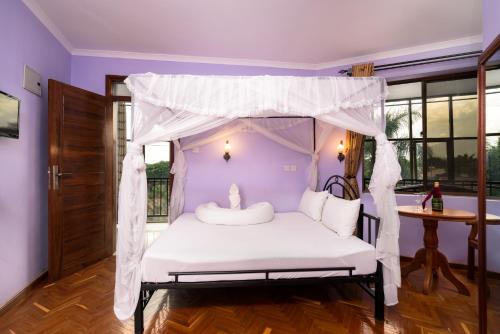 a bedroom with a bed with a canopy at Mrimba Palm Hotel in Arusha