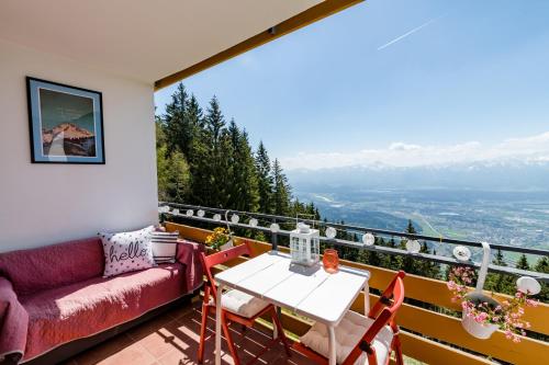 a balcony with a couch and a table and chairs at MOOKI Mountain & Pool Gerlitzen Apartment in Kanzelhöhe