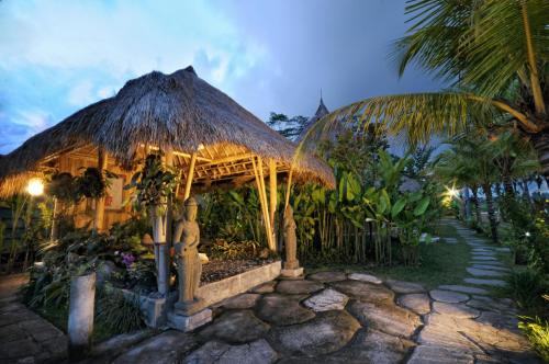 a building with a thatch roof and a path at Ubud Art Resort in Ubud