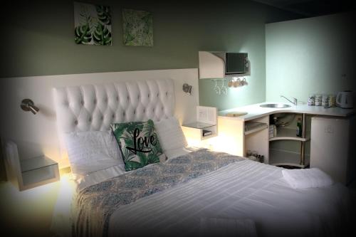 a bedroom with a large white bed with a desk at Serendipity NO TV in Polokwane