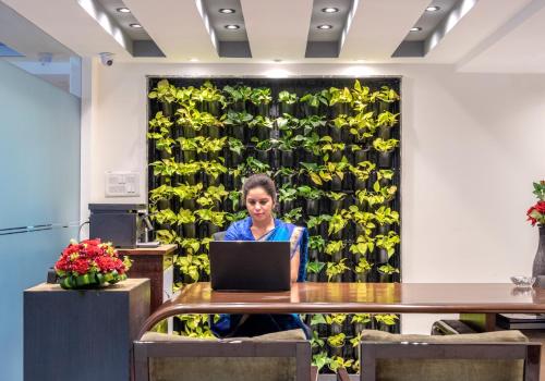 een vrouw aan een tafel met een laptop bij Virohaa Hotel in New Delhi