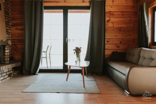 ein Wohnzimmer mit einem Sofa und einem Tisch mit Blumen darauf in der Unterkunft Sielanka Mazurska in Lepaki Wielkie
