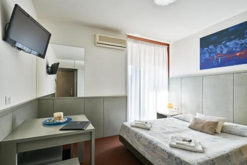 a bedroom with a bed and a desk and a television at Hotel Europa in Grado
