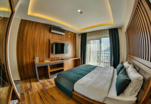 Schlafzimmer mit einem Bett, einem Schreibtisch und einem TV in der Unterkunft DİAMOND LİMAN HOTEL in Bartın