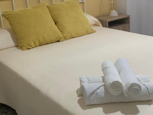 a white bed with three rolled towels on it at Amate con encanto in Seville