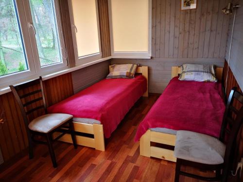 two beds in a room with two chairs and windows at Rita's Guest House in Palanga