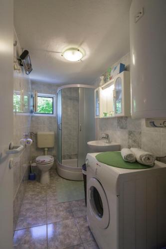 a bathroom with a washer and a toilet and a sink at Heimbring in Rukavac