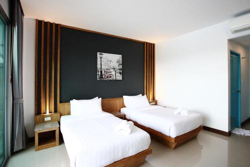 a hotel room with two beds and two lamps at The Malika Hotel - SHA Extra Plus in Phuket Town