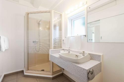a white bathroom with a sink and a shower at The Parnell Hotel & Conference Centre in Auckland