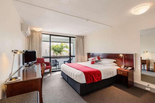 a hotel room with a bed and a desk with a television at The Parnell Hotel & Conference Centre in Auckland