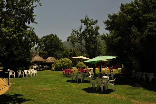 a group of tables and chairs with umbrellas in a park at El Copihue Olmué in Olmué