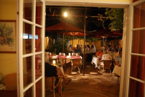 un groupe de personnes assises à des tables dans un restaurant dans l'établissement Auberge des Glycines, à Porquerolles