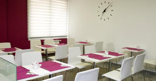 a dining room with tables and white chairs and a clock at Hotel Vila da Guarda in A Guarda