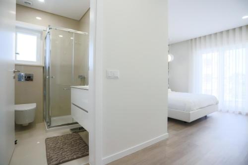 a white bathroom with a shower and a bed at Pajaro Residence in Figueira da Foz