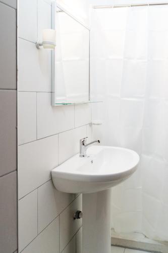 a white bathroom with a sink and a mirror at Villa Juri Garden in Berat