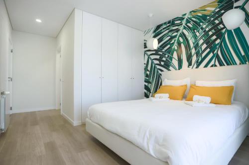 een slaapkamer met een groot wit bed met tropisch behang bij Pajaro Residence in Figueira da Foz