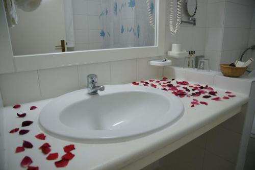 a bathroom sink with red rose petals on it at Afroditi in Panormos Skopelos