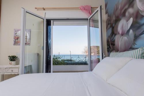 a bedroom with a white bed and a large window at Boutique Apartment Volos in Volos