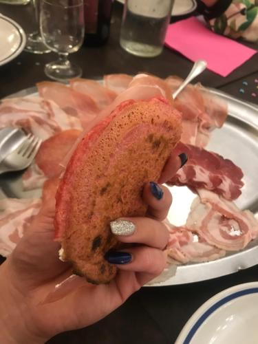 a person holding a sandwich in front of a plate of meat at Hotel Mirador in Aulla