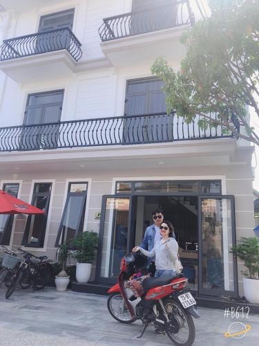 a man and woman riding a motorcycle in front of a building at Peaceful House Hostel in Dong Hoi