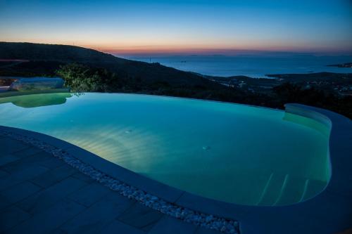 a large swimming pool with a sunset in the background at Villa Aeolos with 2 private pools in Sarakíniko