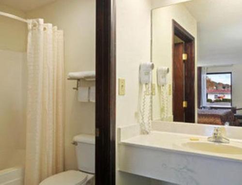 a bathroom with a toilet and a sink and a mirror at Days Inn by Wyndham Attalla in Attalla