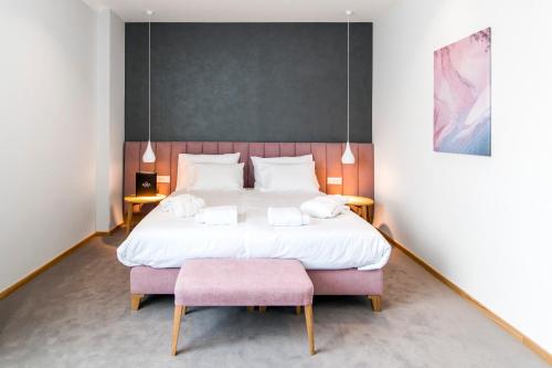 a bedroom with a large bed and a pink stool at Korpa Deli Rooms in Novi Sad